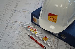 Bauplanung mit Bauplan, Zollstock und Schutzhelm von SF‑Ausbau – professioneller Innenausbau, Sanierung und Bauprojekte in Freiberg und Umgebung.
