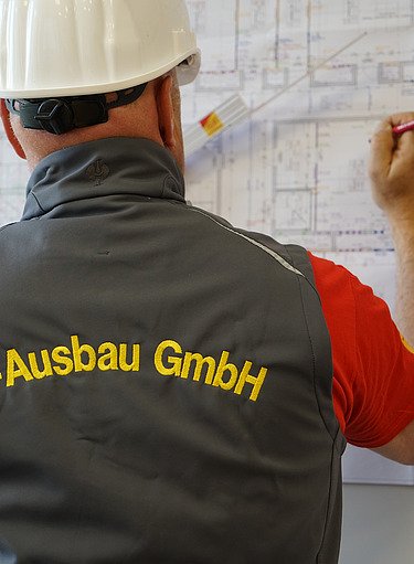 Mitarbeiter von SF‑Ausbau bei der technischen Bauplanung vor einem Ausführungsplan – professionelle Projektsteuerung, Innenausbau, Sanierung und schlüsselfertiges Bauen in Freiberg und Sachsen.