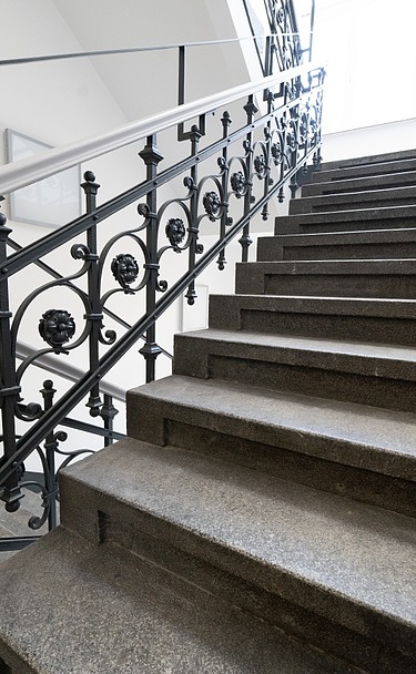 Saniertes Treppenhaus mit Natursteinstufen und denkmalgerechtem Metallgeländer im Verwaltungsgebäude an der Hansastraße in Dresden – hochwertige Sanierung und schlüsselfertiger Innenausbau durch SF‑Ausbau.