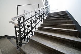 Saniertes Treppenhaus mit Natursteinstufen und denkmalgerechtem Metallgeländer im Verwaltungsgebäude an der Hansastraße in Dresden – hochwertige Sanierung und schlüsselfertiger Innenausbau durch SF‑Ausbau.