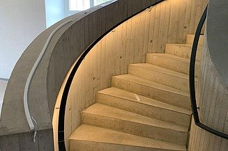 Geschwungene Betontreppe mit integrierter LED-Beleuchtung und moderner Elektroinstallation im Blockhaus Dresden – hochwertiger Innenausbau und Elektroarbeiten von SF‑Ausbau.