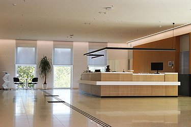 Moderner Empfangsbereich mit Rezeption, Sitzbereich und Beleuchtung – hochwertiger Innenausbau und Trockenbau im Gewerbeobjekt durch SF‑Ausbau in Freiberg.
