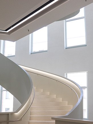 Geschwungene Designtreppe mit integrierter LED-Beleuchtung und hochwertiger Akustikdecke im Hörsaalzentrum der TU Bergakademie Freiberg – präziser Trockenbau und moderner Innenausbau von SF‑Ausbau.
