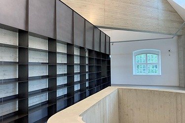 Modern gestalteter Innenraum mit großem Regalsystem, Sichtbeton und Holzdecke – präziser Innenausbau und Elektroarbeiten durch SF‑Ausbau in Dresden und Freiberg.