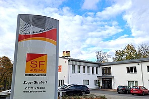Firmengebäude von SF‑Ausbau in Freiberg mit Unternehmensstele und Firmenlogo – Experte für Neubau, Sanierung, Innenausbau und schlüsselfertige Bauprojekte in Sachsen.