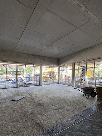 Innenraum im Rohbau des Karl-May-Museums in Radebeul mit großflächigen Fensterfronten, Sichtbeton und vorbereiteten Trockenbauarbeiten – professioneller Innenausbau und schlüsselfertiges Bauen durch SF‑Ausbau.